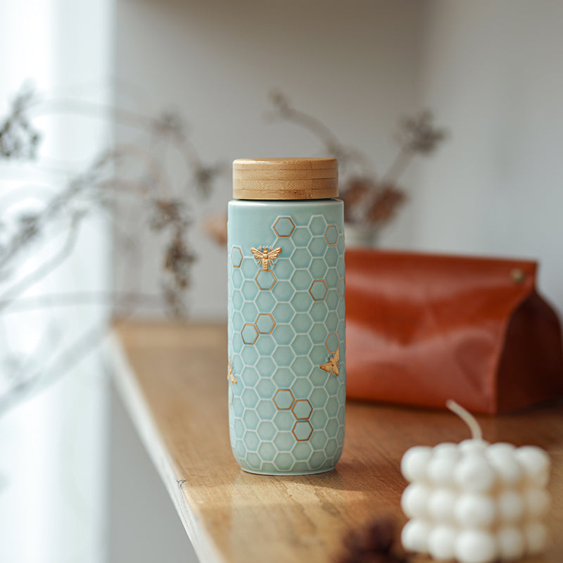Experience pure taste and modern style with the ACERA Honey Bee travel mug. The tourmaline lining enhances the flavor and freshness of any beverage, while the handcrafted honeycomb design and golden honey bees on the ceramic outer layer create a unique look.